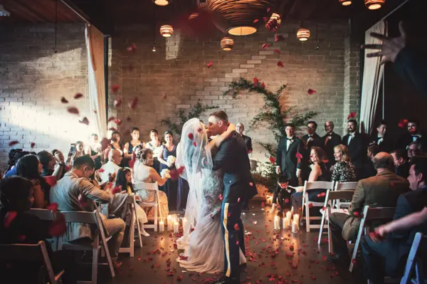 Indoor Seattle-area wedding ceremony with rose petal toss and candlelit aisle. Lovely Events.