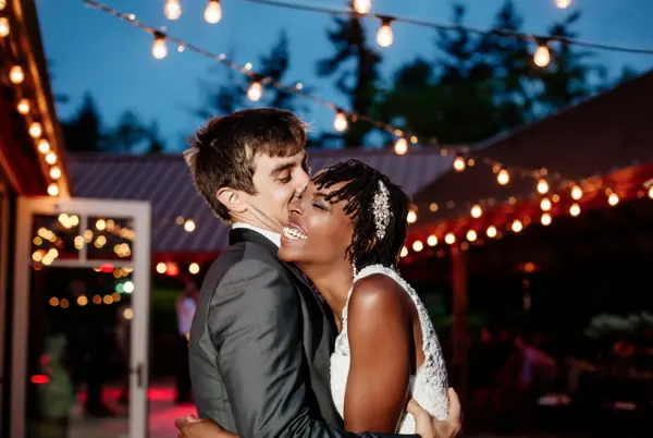 Bride and groom dancing at evening outdoor Washington wedding reception with string lights. Lovely Events.