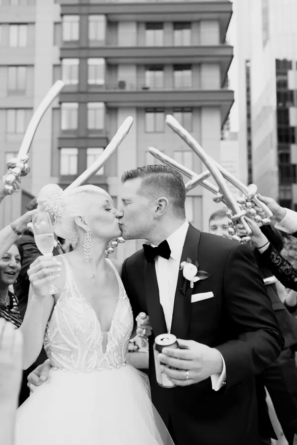Bride and groom kissing under arch of balloon swords at urban Seattle-area wedding. Lovely Events.